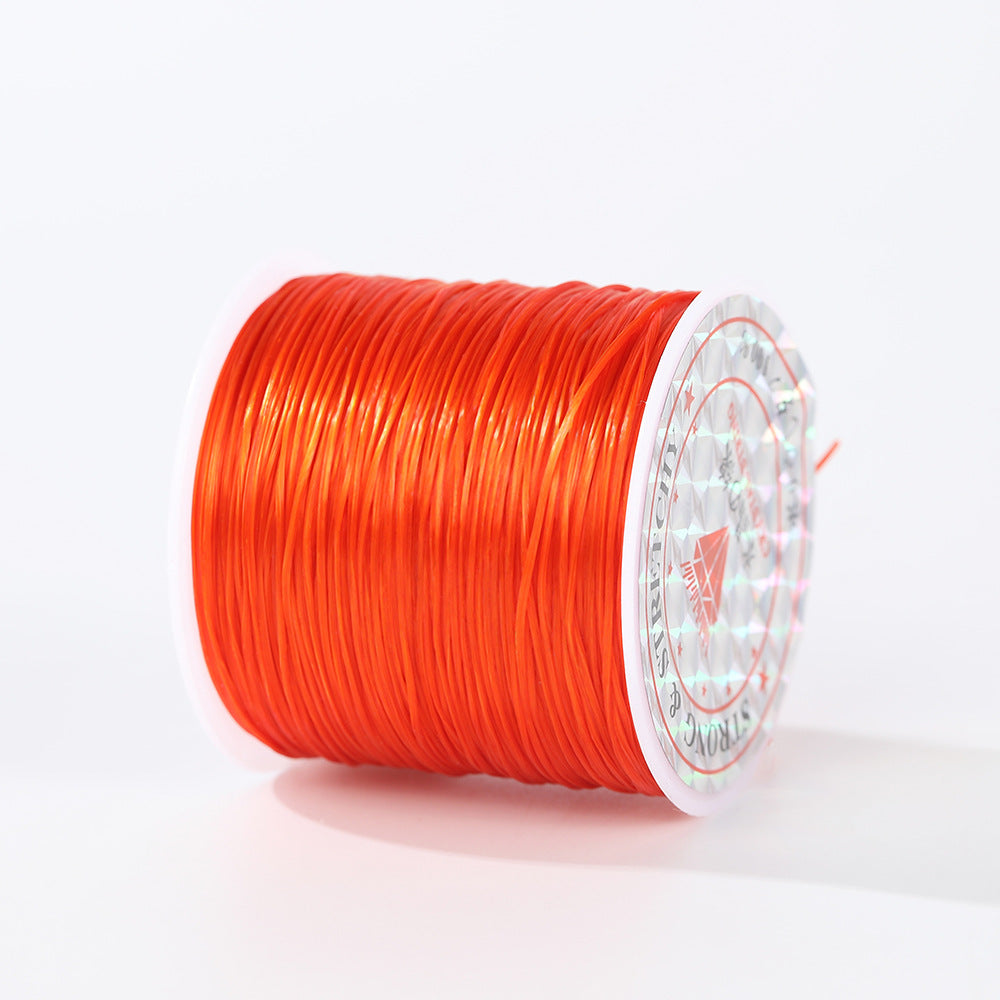 Spool of orange-red 0.8mm flat elastic beading cord on its side, holographic label, loose strand at right, white background