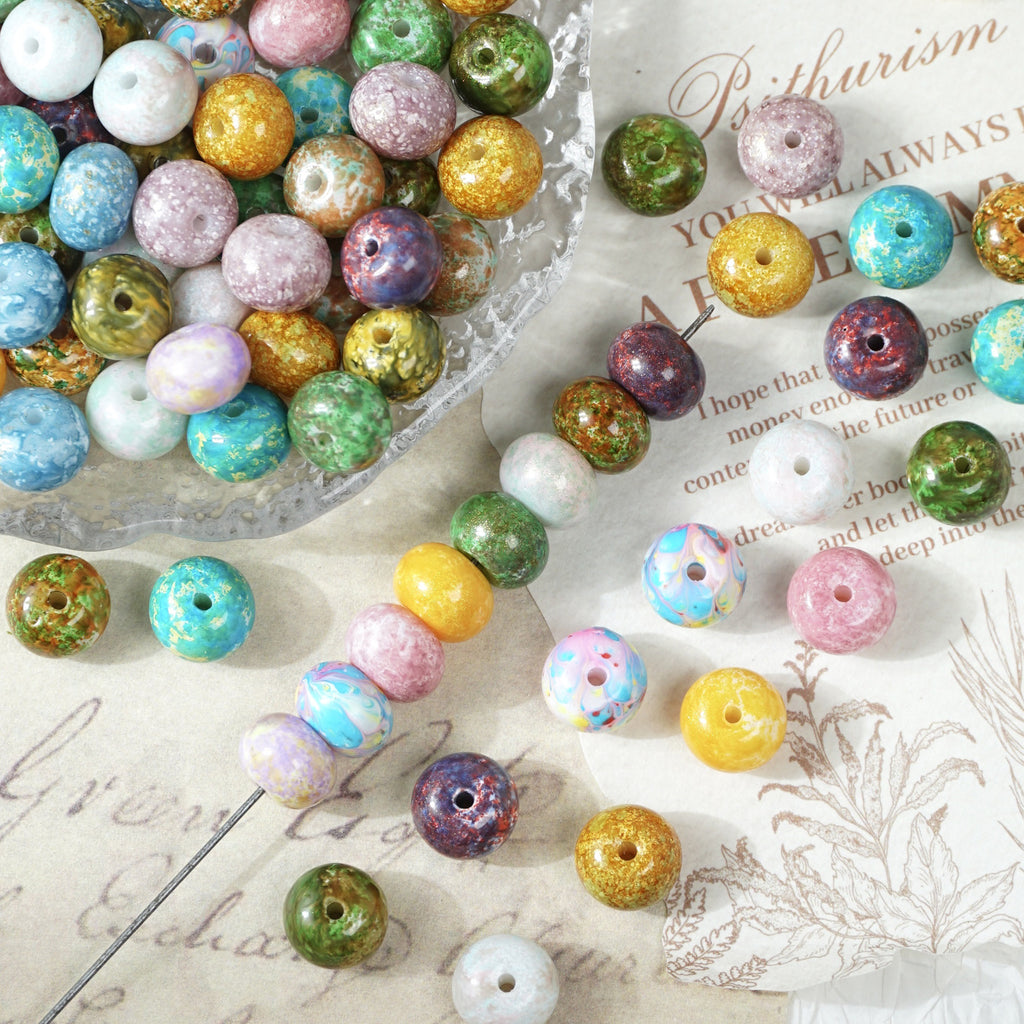 Multicolor oil-painting imitation porcelain abacus beads scattered on printed paper with a porcelain dish
