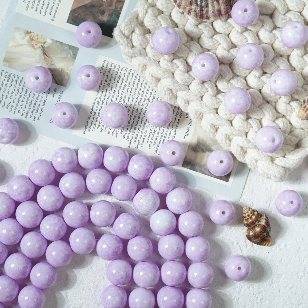 Light purple marbled round glass beads with holes on a white textured surface
