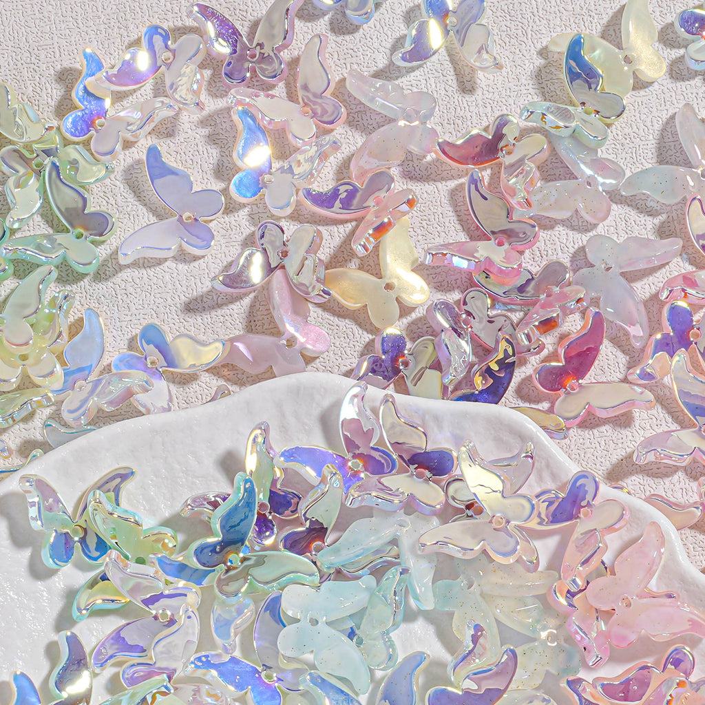 Iridescent butterfly acrylic beads scattered on textured background with white dish of pastel beads