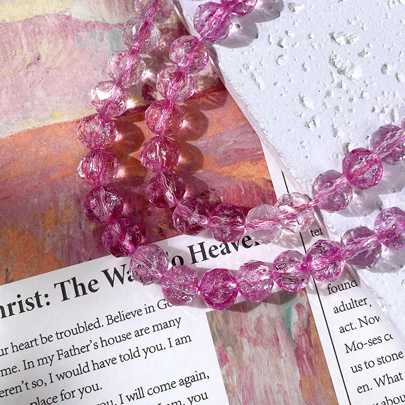 Close-up of a pink beaded bracelet made of faceted glass beads with internal sparkles over printed paper