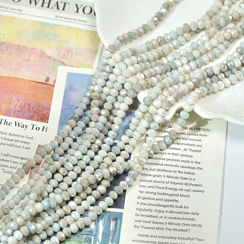 Light gray and white marbled faceted porcelain bead strand on open books