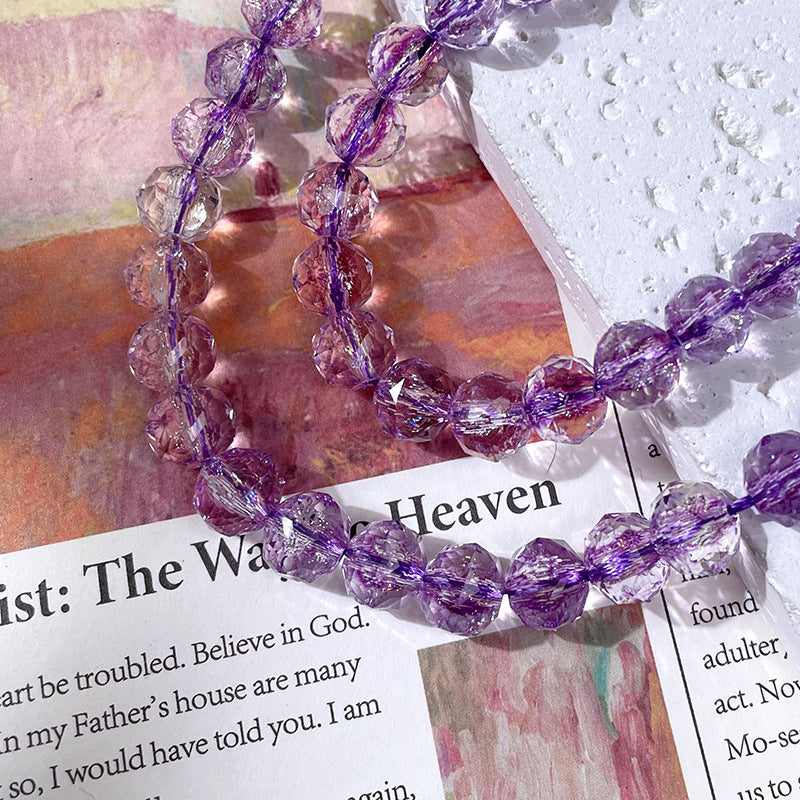 Beaded necklace of faceted purple and clear beads on purple cord over an open book with printed text
