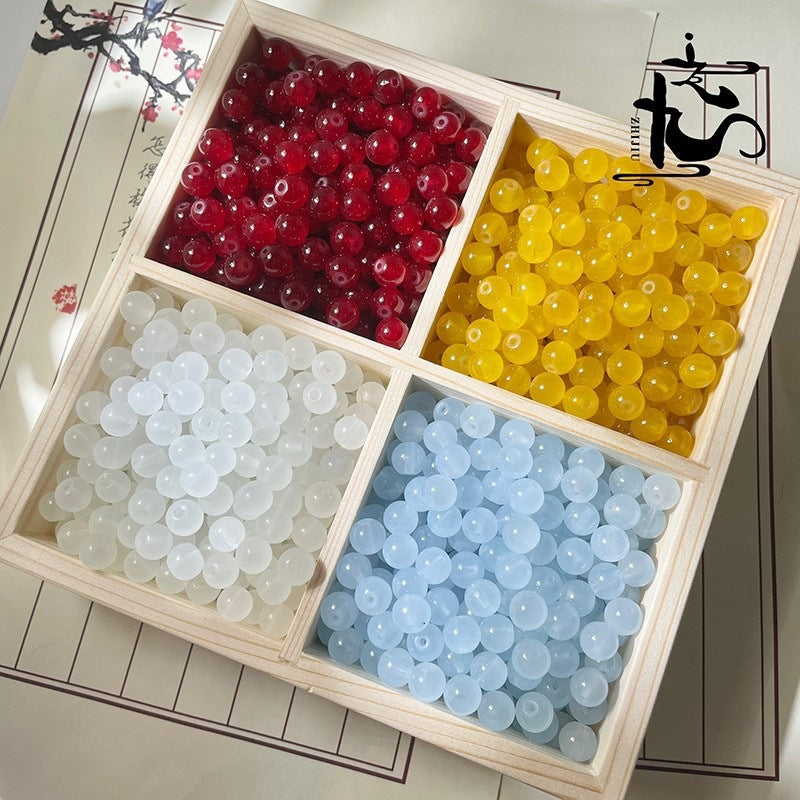 Wooden divided tray with red, yellow, white, and light blue beads on decorative paper
