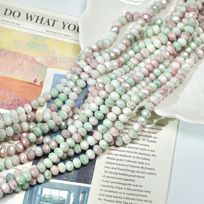 Strands of pastel pink, mint green, and white faceted porcelain beads on a book and dish