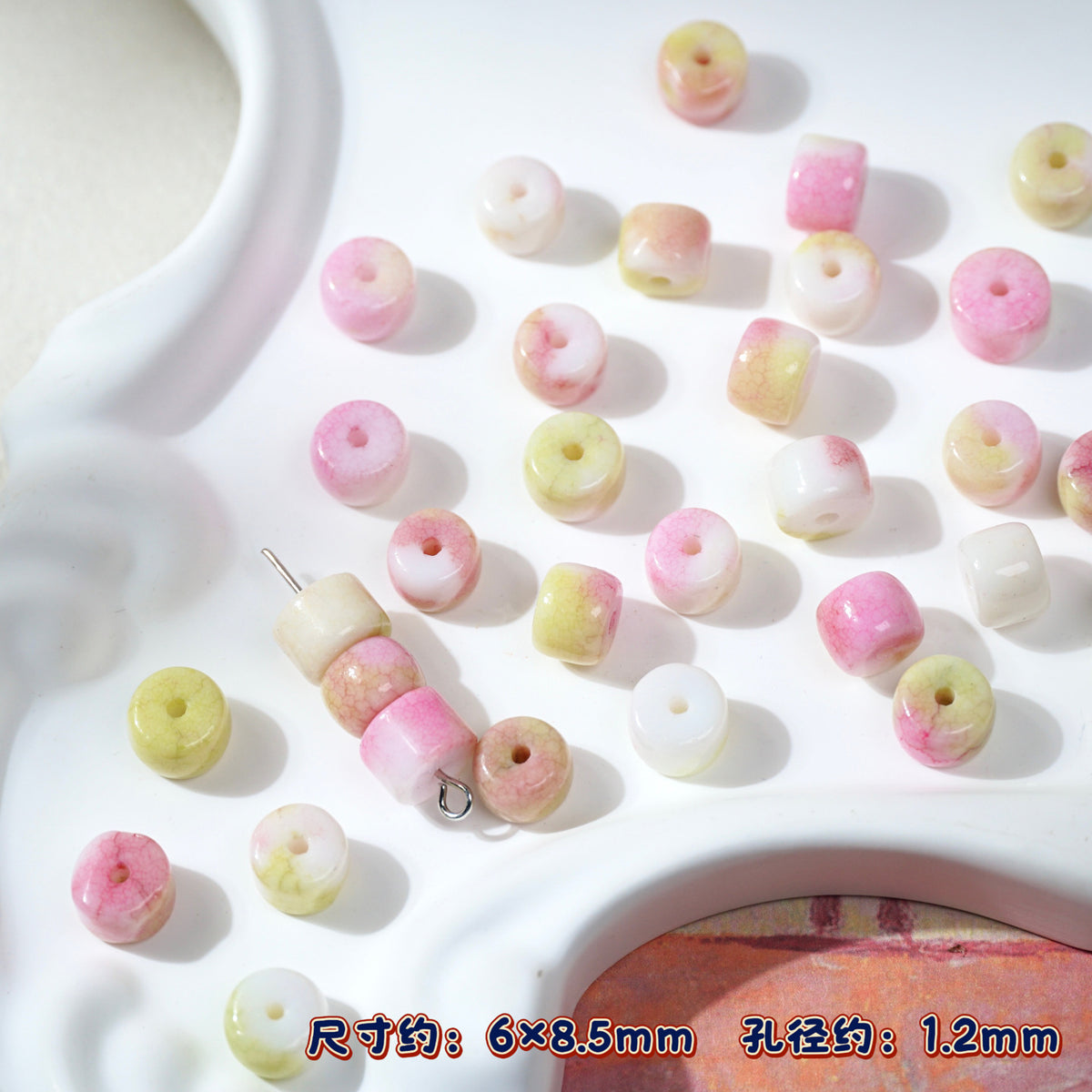 Pink, yellow, white marbled round porcelain beads on white ceramic tray