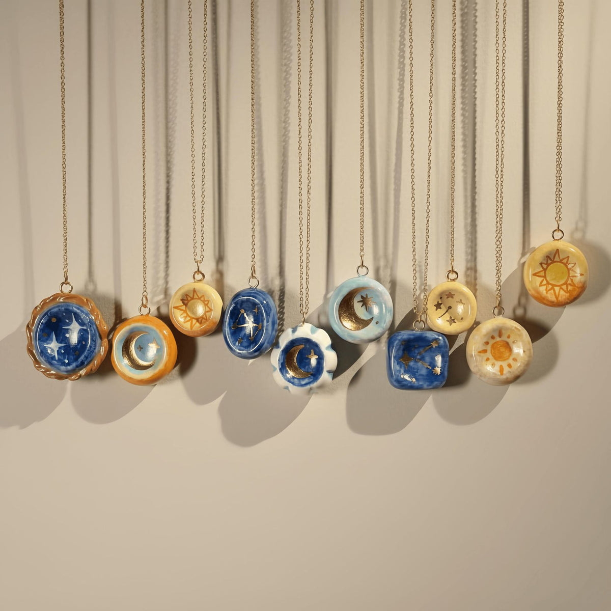 Necklaces with unique pendant designs hanging against a neutral background