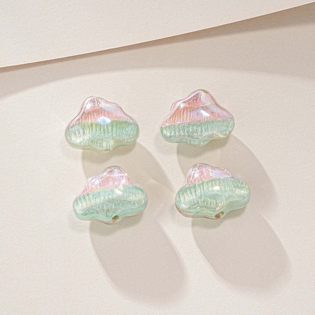 Four small cloud-shaped translucent beads with pearly iridescent finish in mint green and pink on off-white.
