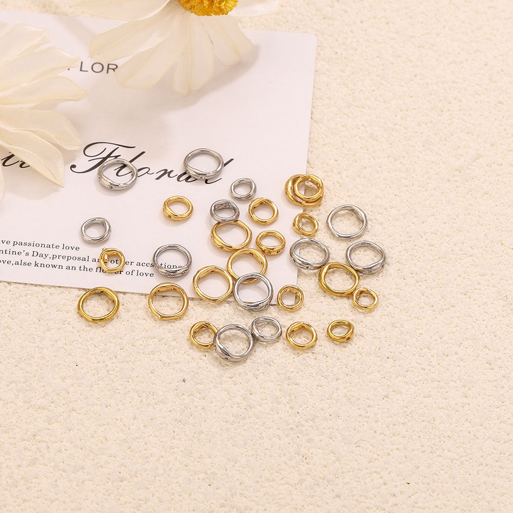 Gold and steel color double-ring spacer connectors scattered on cream textured surface with floral card