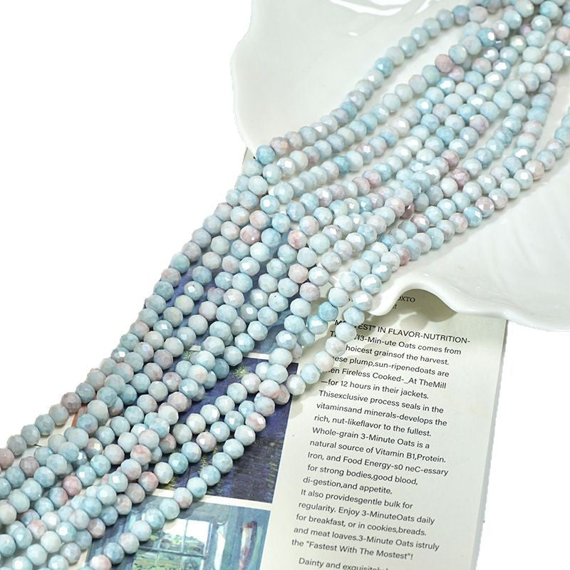 Long strand of pastel faceted porcelain beads in pale blue, pink, and white laid diagonally