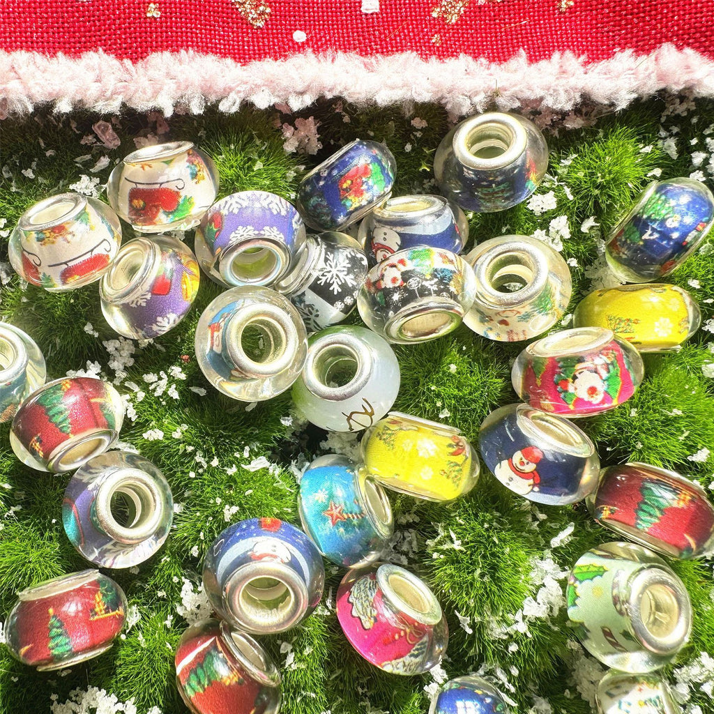 Pile of small clear acrylic beads with colorful Christmas designs on green background
