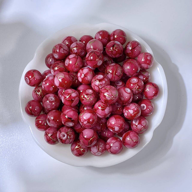 White bowl of marbled rose-red glass beads with gold-silk veining