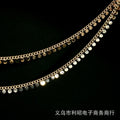 Two strands of gold-toned disc chain with small round metallic discs on a black background.
