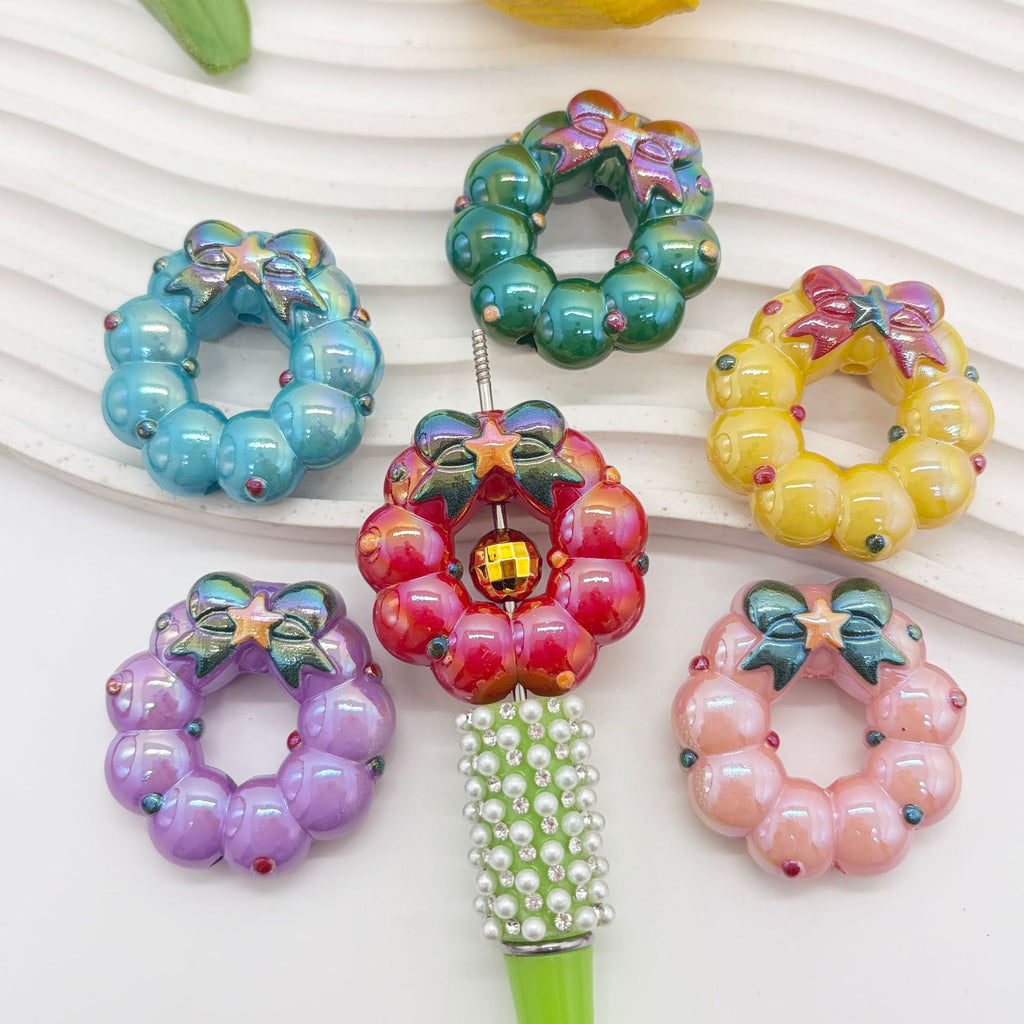 Six colorful wreath-shaped acrylic focal beads with bows and stars in blue, green, yellow, red, purple and pink
