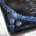 Strand of blue water-ripple lampwork glass beads on a black tray with three loose beads, over printed book text
