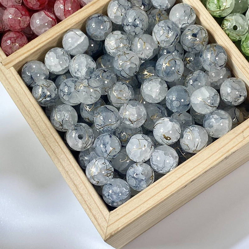 Clear crackle glass beads with gold-silk veins in a wooden tray