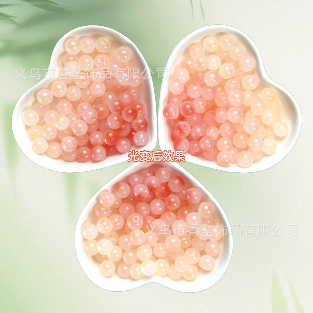 Three heart-shaped dishes of translucent peach and pink beads on pale green