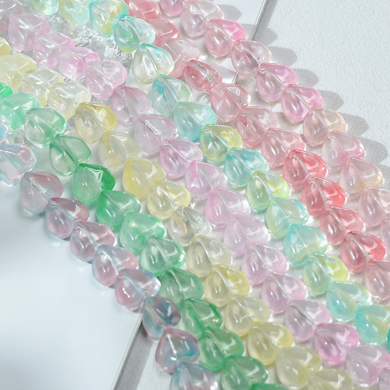 Close-up of translucent pastel heart-shaped glass beads in pink, green, blue, yellow and lavender on a white surface
