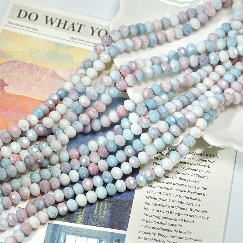 Overlapping strands of pastel lavender, light blue, and soft pink faceted beads on a book