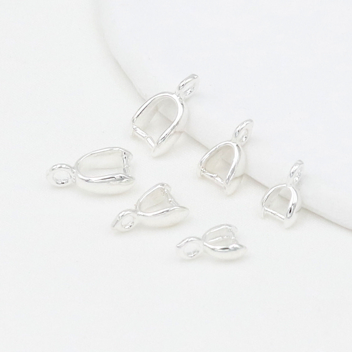 Silver pinch bail pendant clasps with leaf-shaped cups on a white background