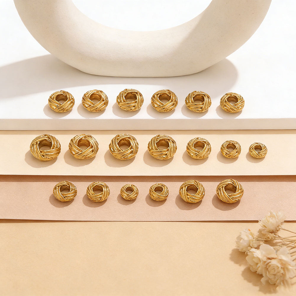 Gold-tone woven bird's nest beads arranged in rows on beige paper strips