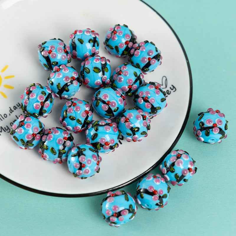 Blue glass pendant beads with pink cherry blossom pattern on a white plate