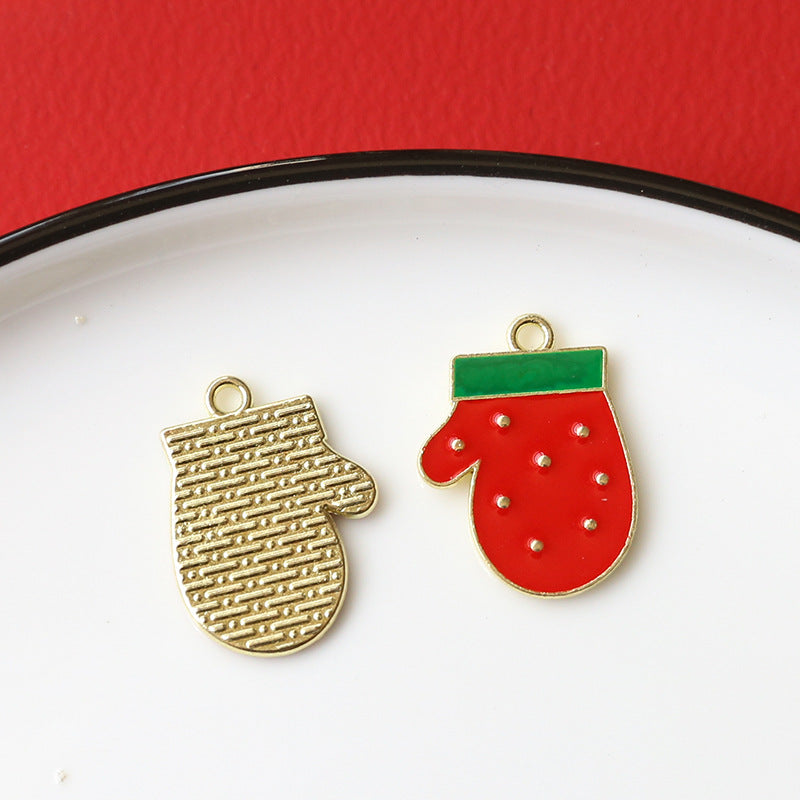 Two small holiday-themed enamel mitten charms on white plate with red background