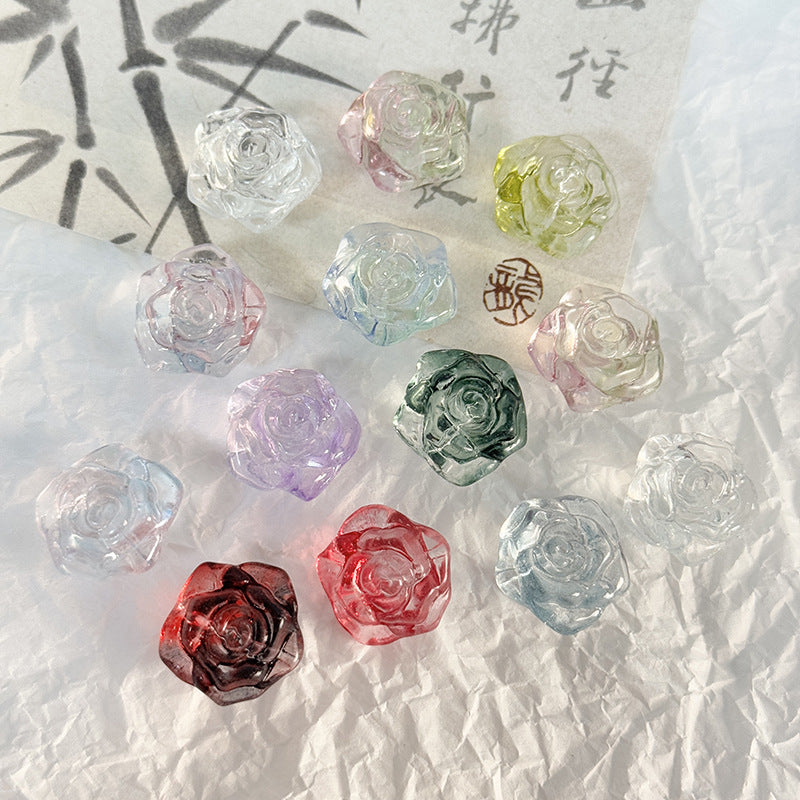 Faceted rose-shaped crystal glass beads in clear, pink, green, purple, red and blue on white paper with calligraphy accent