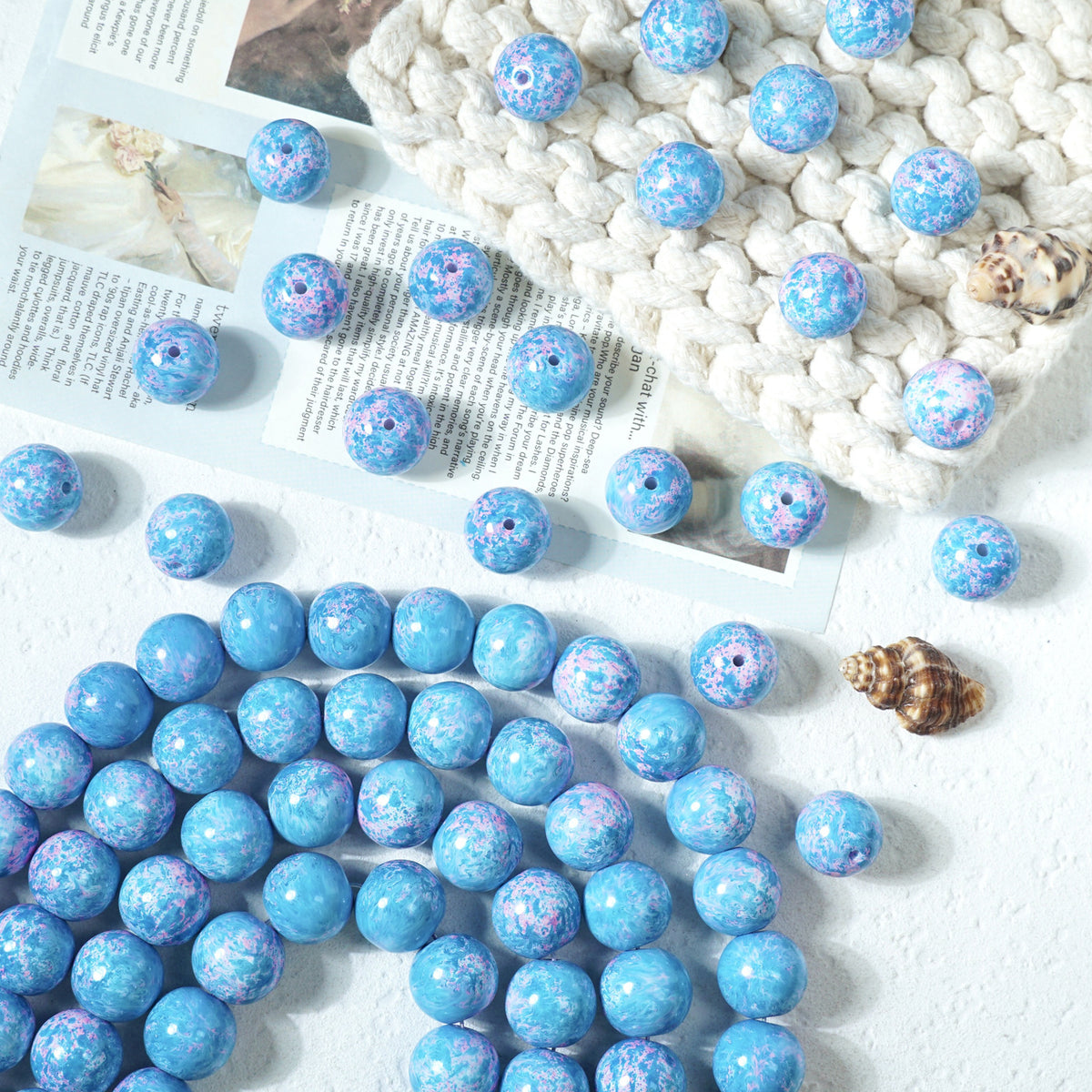Blue marbled round glass beads with white and purple speckles on a white surface