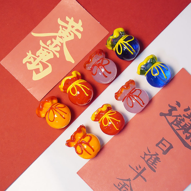Eight pouch-shaped glass beads in red, orange, pink and blue with bow details on calligraphy paper.