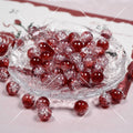 Red glittery round beads with frosted coating on a clear glass plate