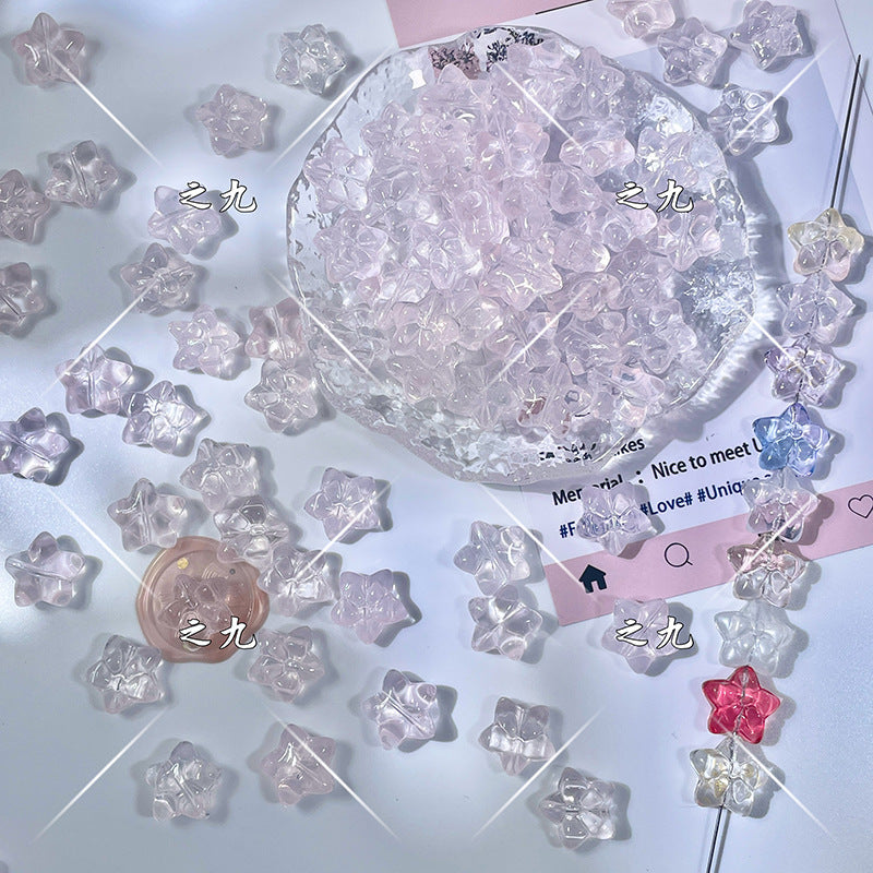 Translucent pastel star-shaped glass beads in pink, purple, blue, and red on a white surface