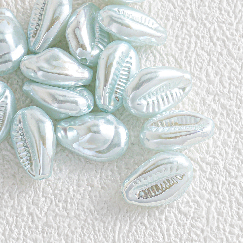 Small glossy iridescent shell-shaped beads scattered on a textured white background