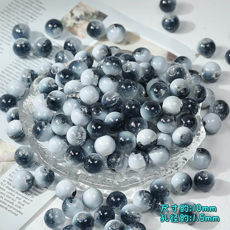 Dark navy and white ice-crackle glass beads piled in a clear textured glass bowl with scattered beads