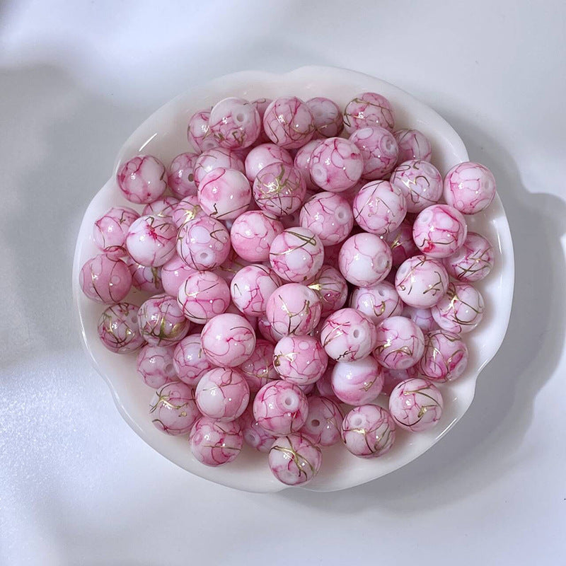 White bowl of marbled pink glass beads with gold-silk veining