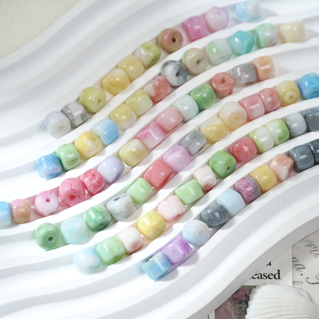 Multicolor cylindrical porcelain barrel beads with marbled pattern in diagonal rows on white