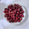 White bowl of marbled red glass beads with gold-silk veining