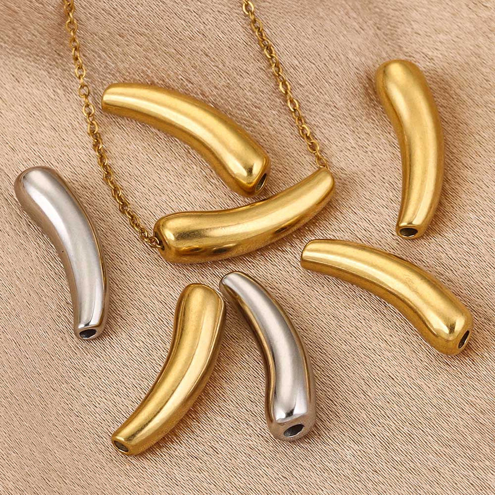 Gold and silver curved tube beads on beige fabric, one threaded on a gold chain