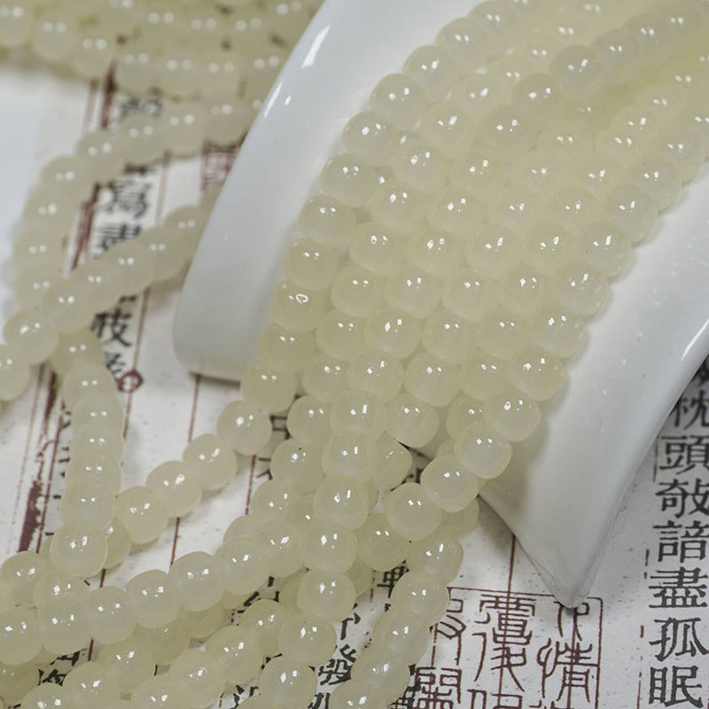 Pale cream translucent round bead strands over a white curved display stand on printed paper with Chinese characters