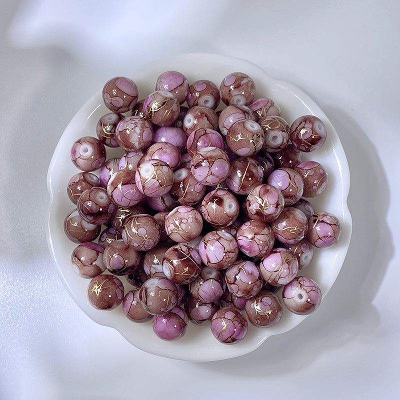 White bowl of marbled mauve-purple glass beads with gold-silk veining