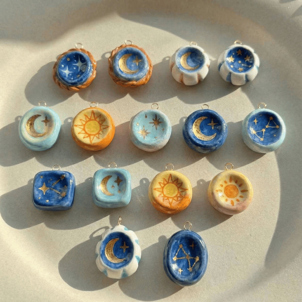 Collection of celestial-themed ceramic pendants on a beige surface