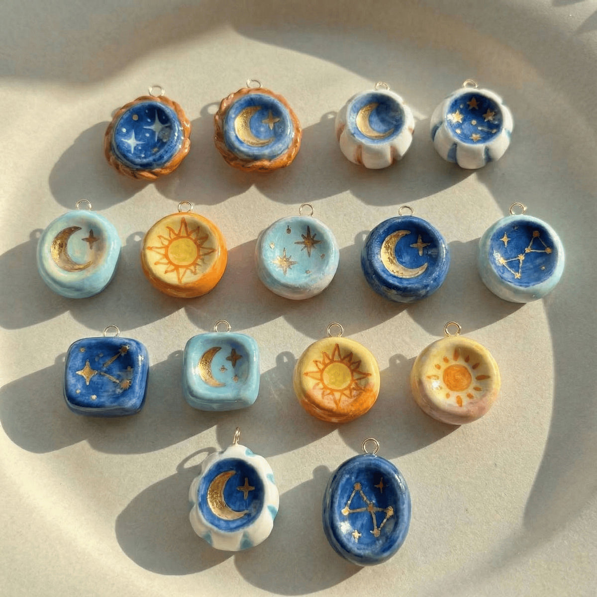 Collection of celestial-themed ceramic pendants on a beige surface