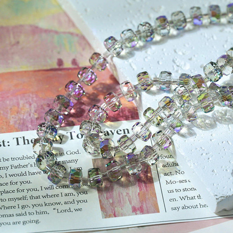 Close-up of a beaded strand with faceted clear beads with an iridescent rainbow sheen resting on printed pages