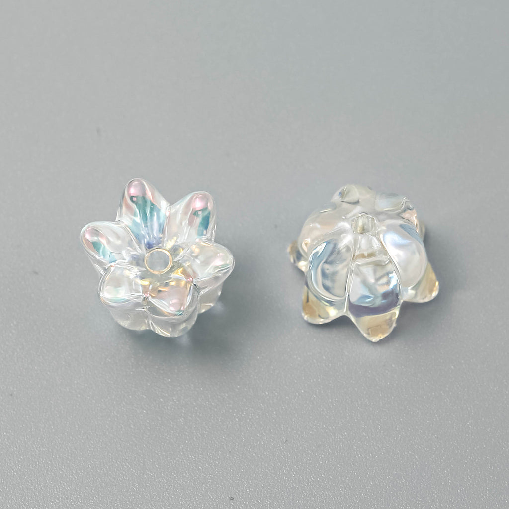 Two clear iridescent lily-shaped beads, one showing front and one showing back, on a neutral gray background