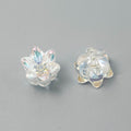 Two clear iridescent lily-shaped beads, one showing front and one showing back, on a neutral gray background