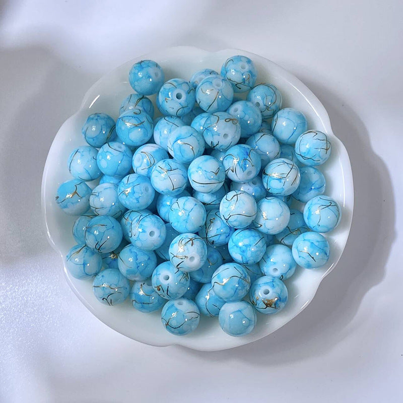 White bowl of marbled light blue glass beads with gold-silk veining