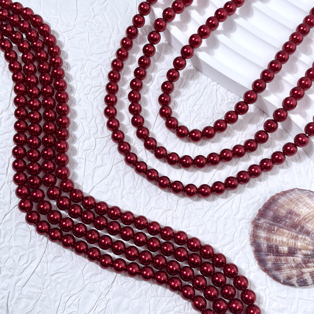 Multiple strands of glossy dark red glass pearl beads with seashell prop