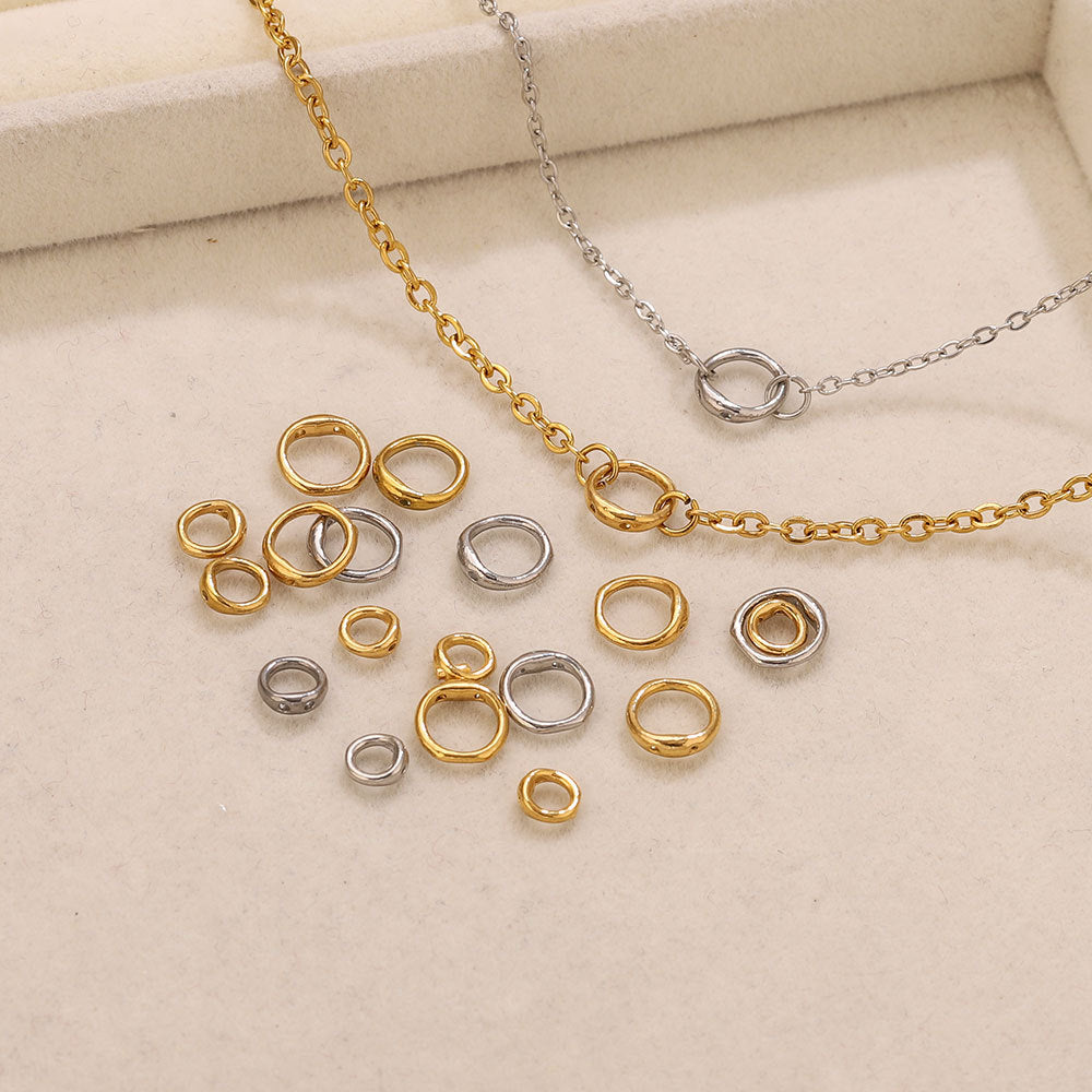 Gold-plated and steel color stainless steel double-ring spacer connectors on cream jewelry box with chains