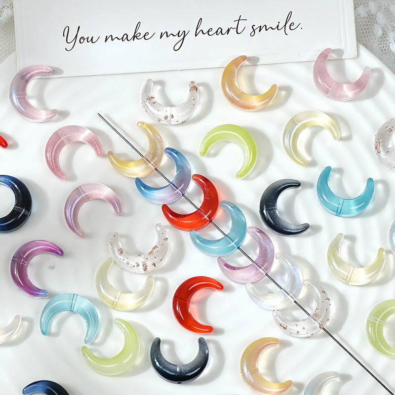Assorted colorful glazed glass crescent moon beads flat-lay on a white surface with a greeting card