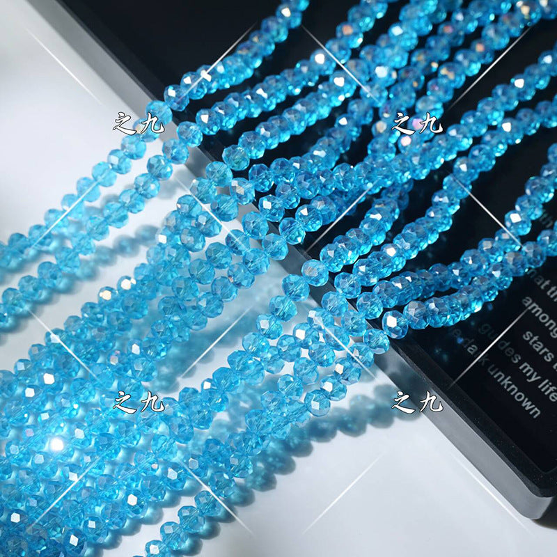 Strands of faceted blue crystal glass wheel beads arranged diagonally on white surface with black edge